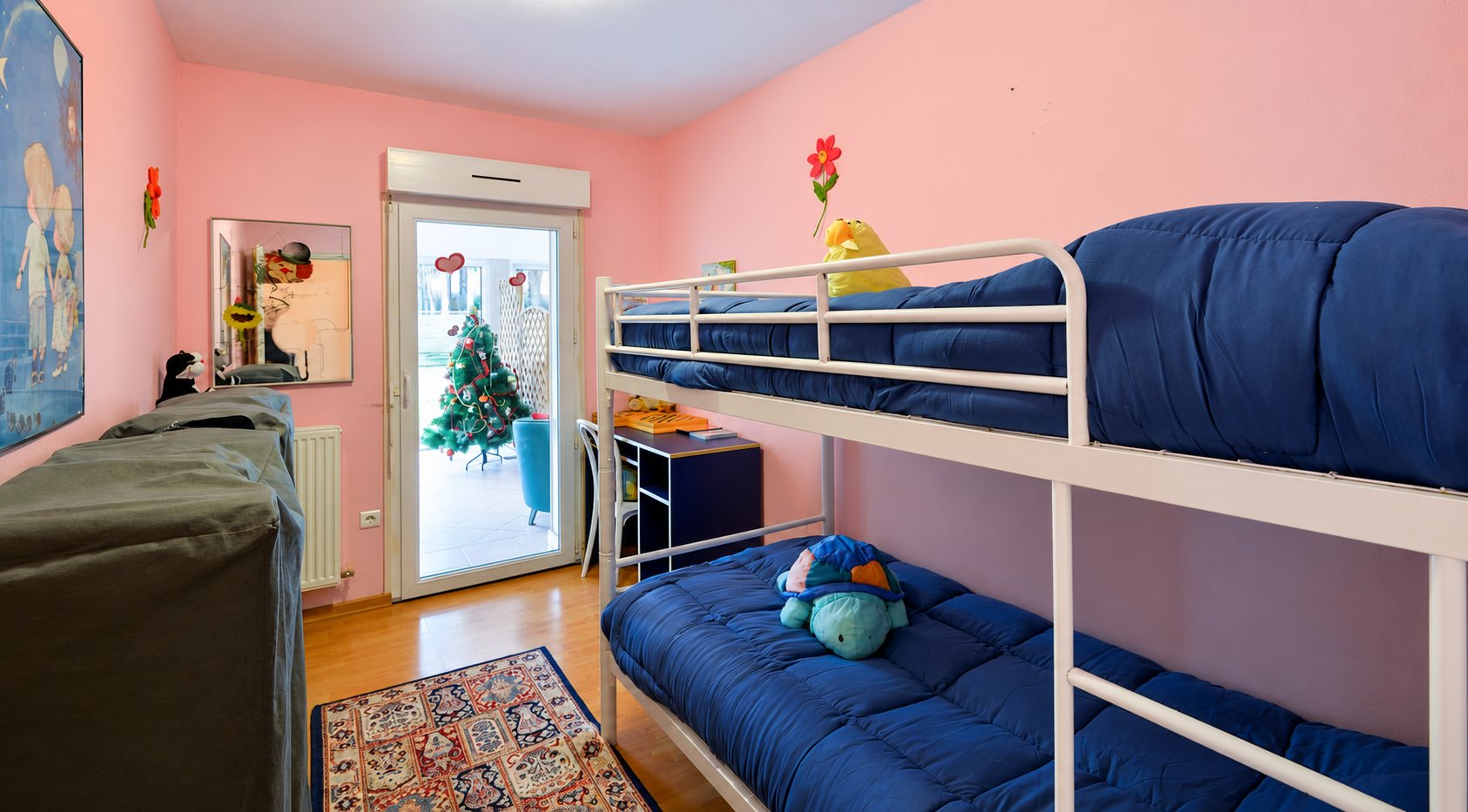 Chambre d’enfant rose avec lits superposés et sapin de Noël en terrasse