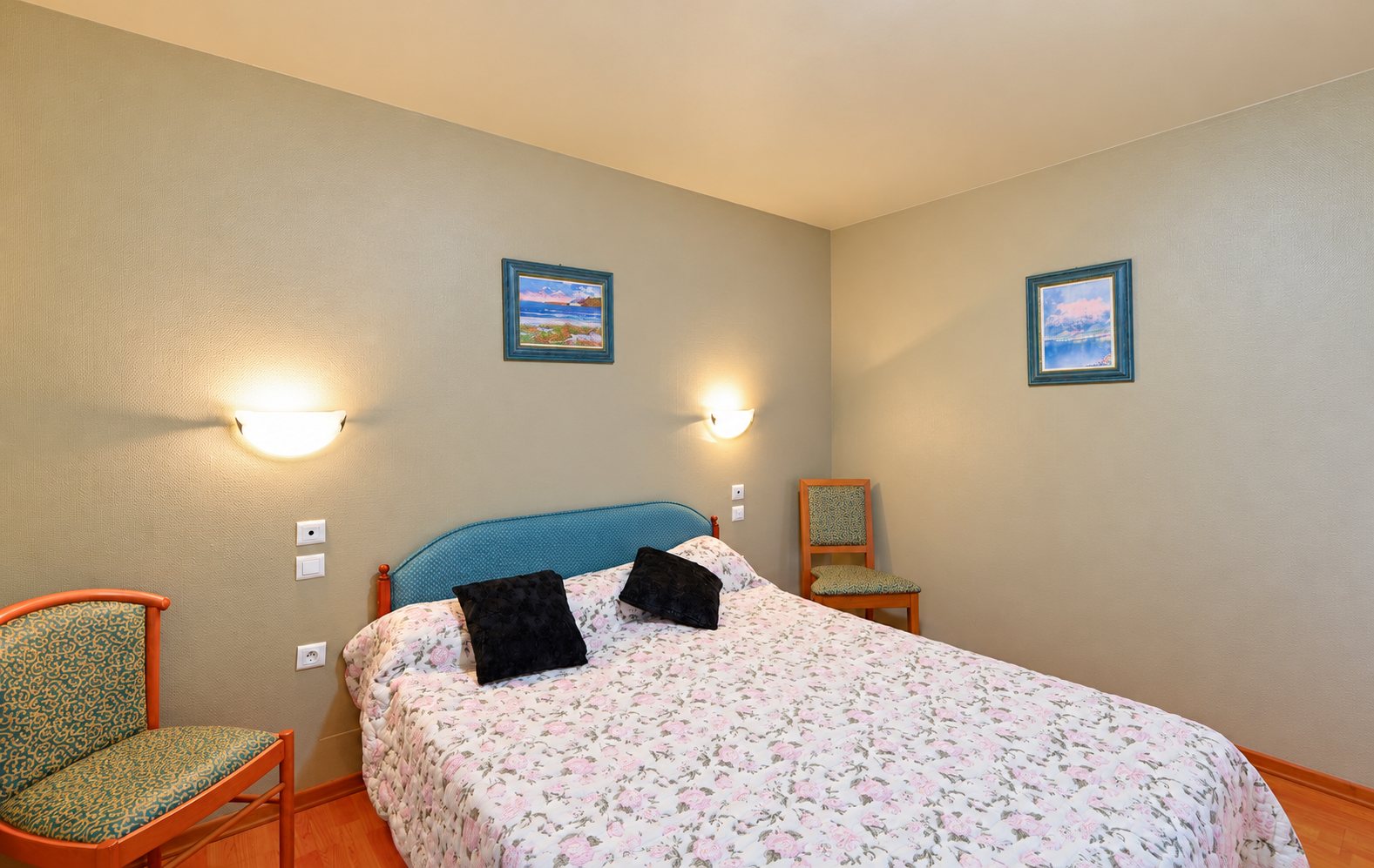 Chambre d’hôtel avec lit double, chaises et appliques murales allumées