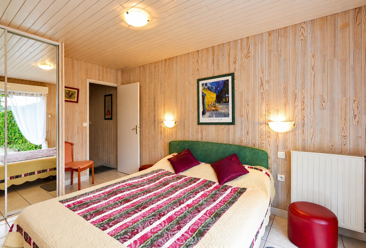 Chambre lambrissée en bois avec lit double et armoire à miroir