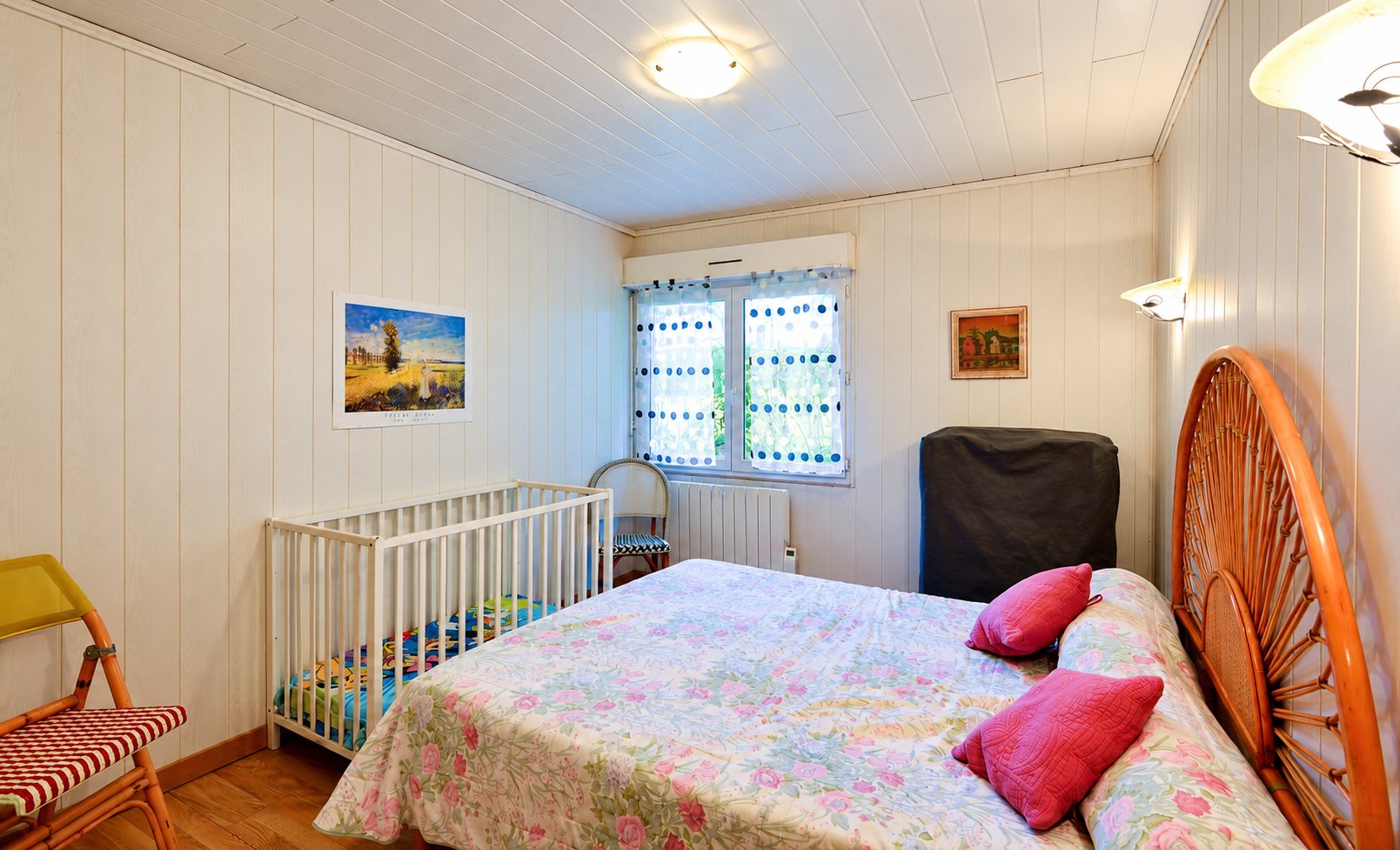 Chambre lumineuse avec lit double, lit bébé et tête de lit en rotin