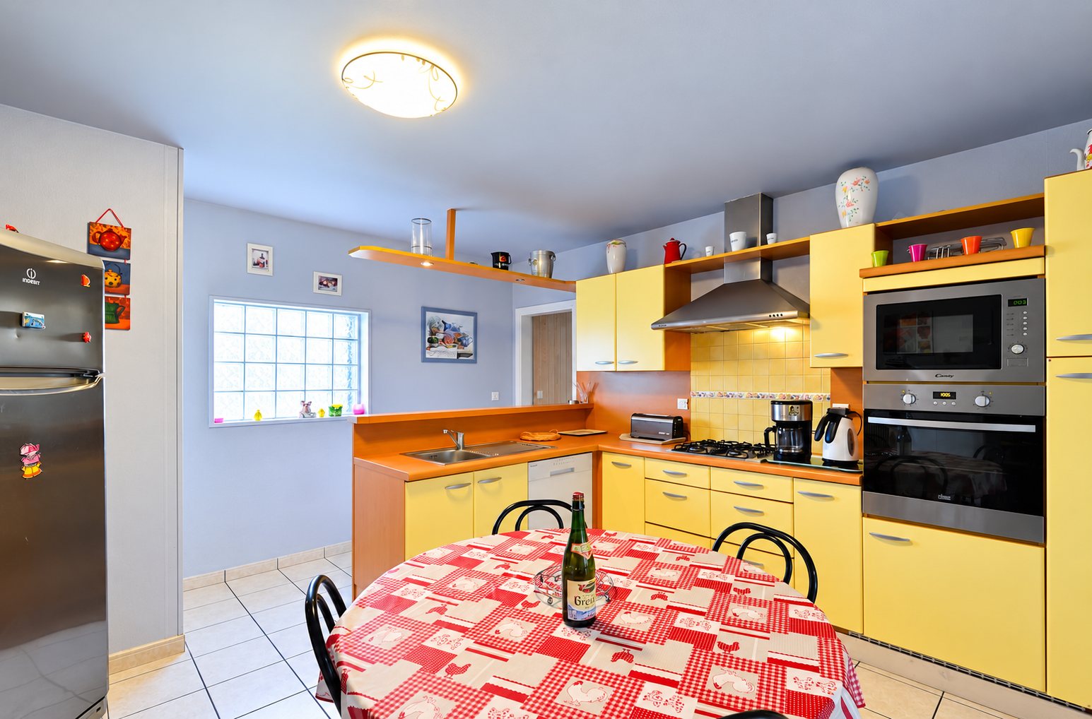 Cuisine équipée jaune et orange avec table à nappe rouge